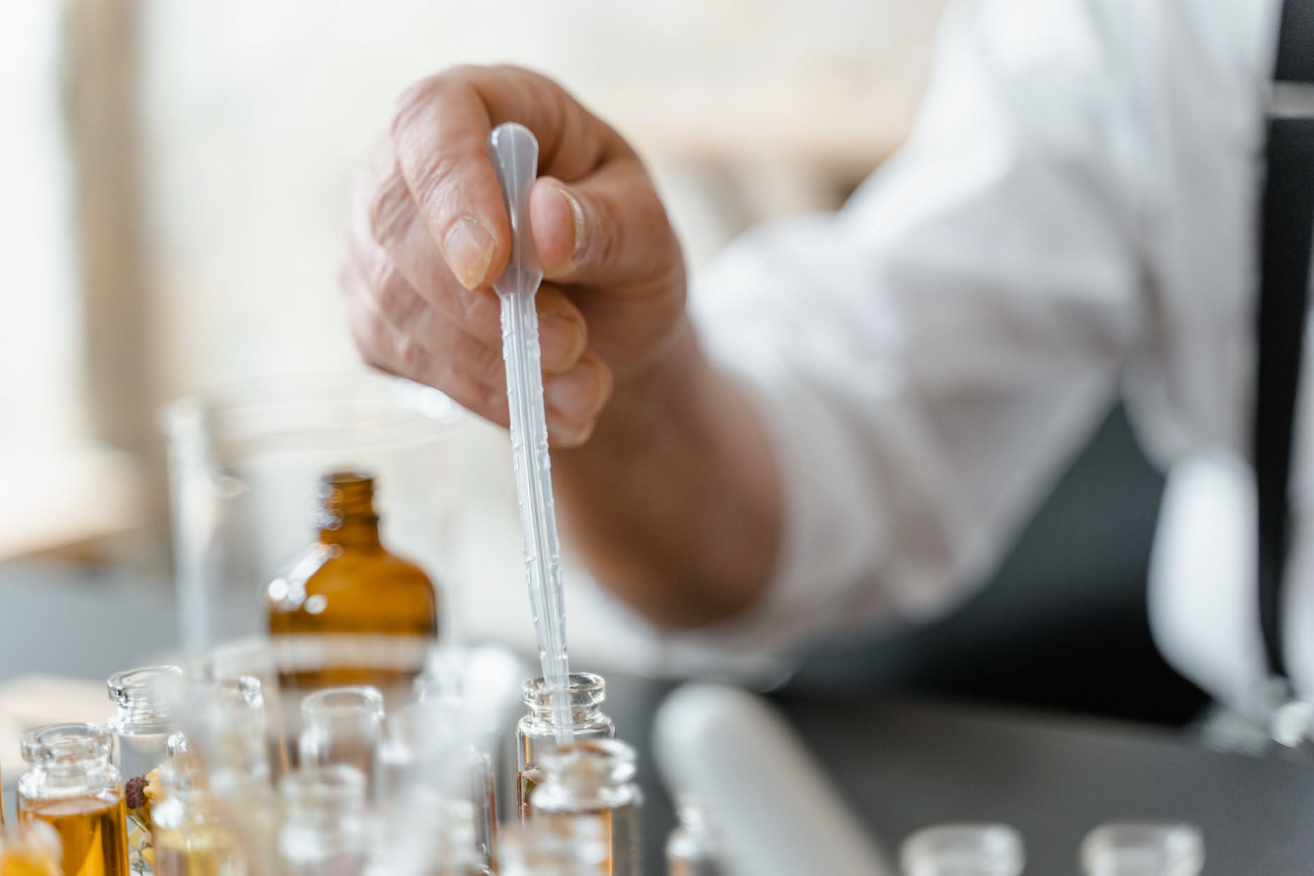Tre flaconi di profumo in vetro trasparente su sfondo bianco, etichettati con eau de parfum, eau de toilette ed extrait, con diversi livelli di liquido profumato