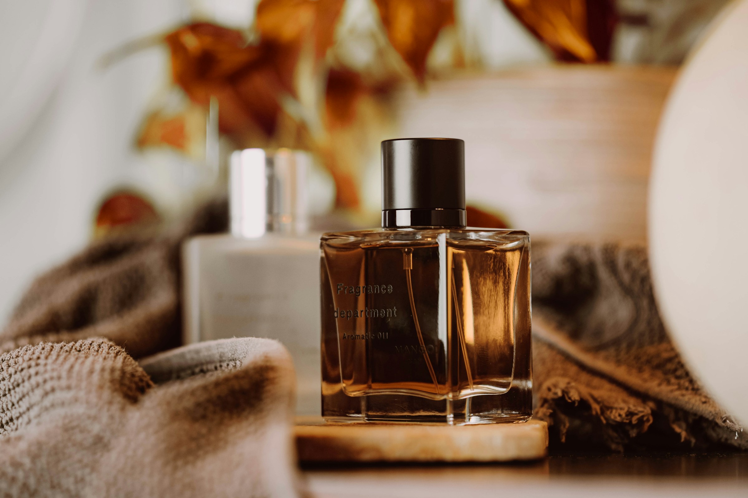 Flaconi di profumi di diverse tonalità e stili disposati in sequenza su una superficie neutra, rappresentando l'evoluzione nel tempo