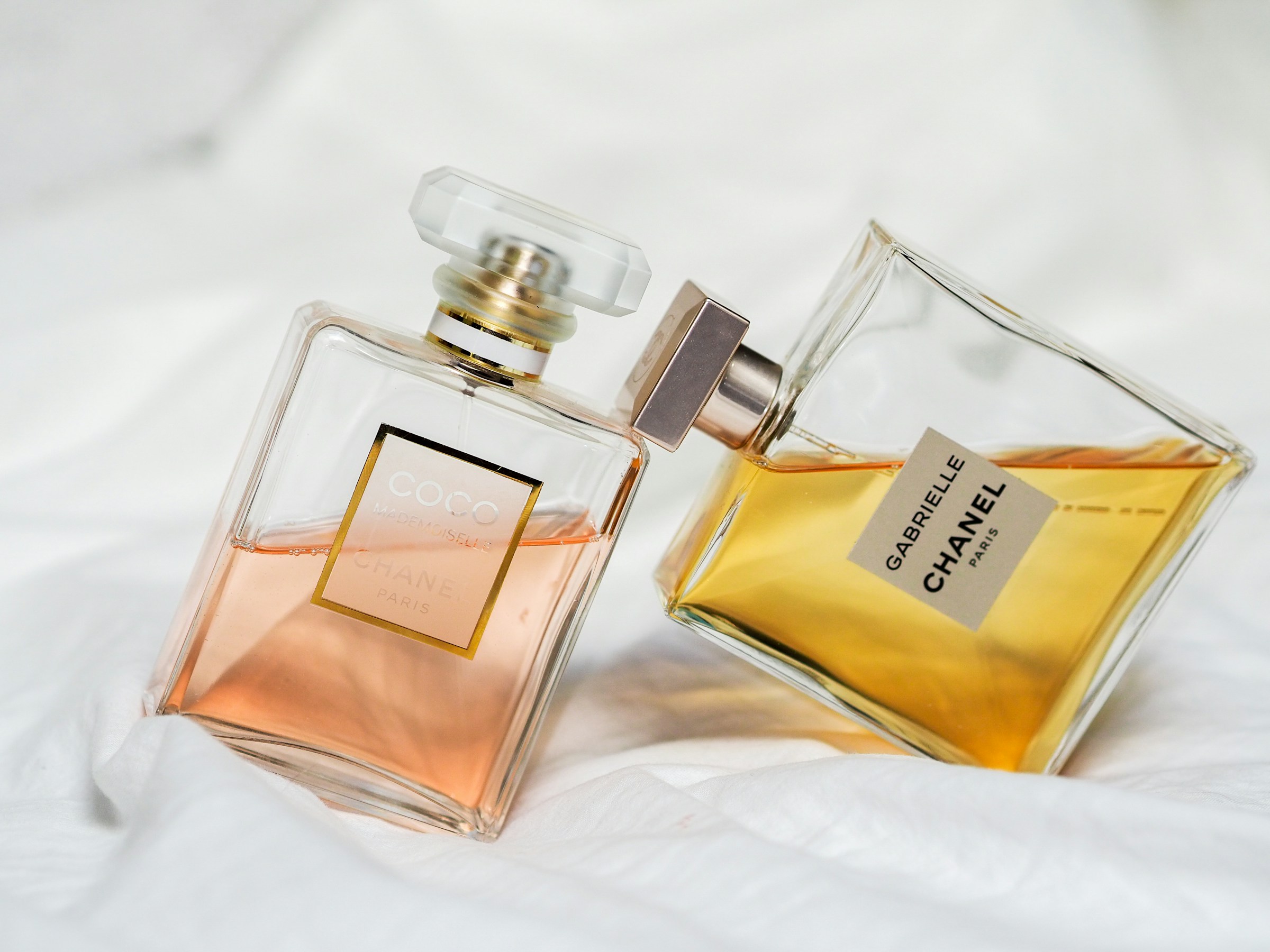Collezione di bottiglie di profumo di diverse epoche su uno sfondo chiaro, dall'Art Déco al design contemporaneo minimalista