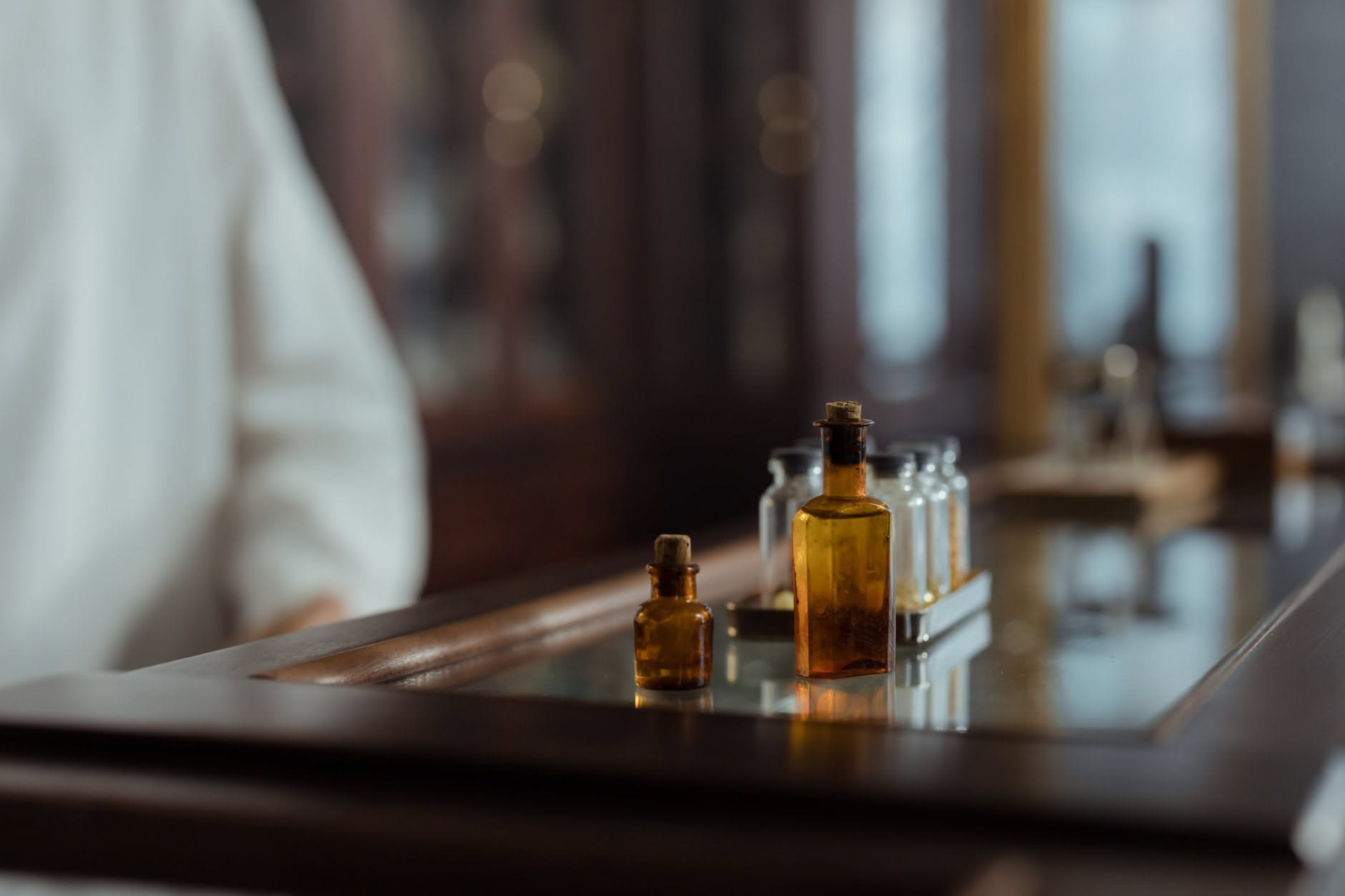 Bottiglia di vetro ambrato con un liquido chiaro accanto a tre boccette di olio essenziale