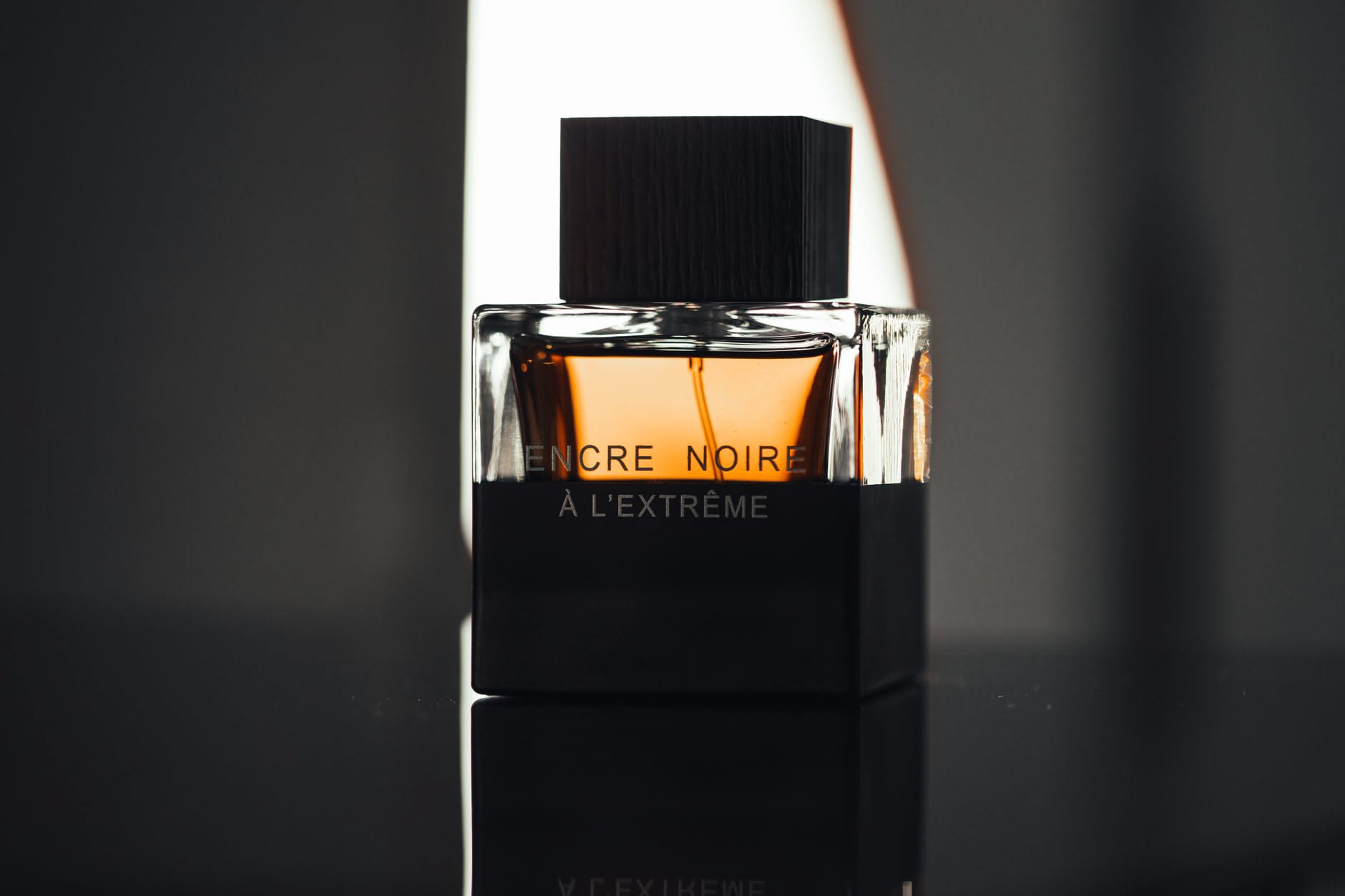 Flacone di profumo maschile accanto a legni, spezie e scorze di agrumi