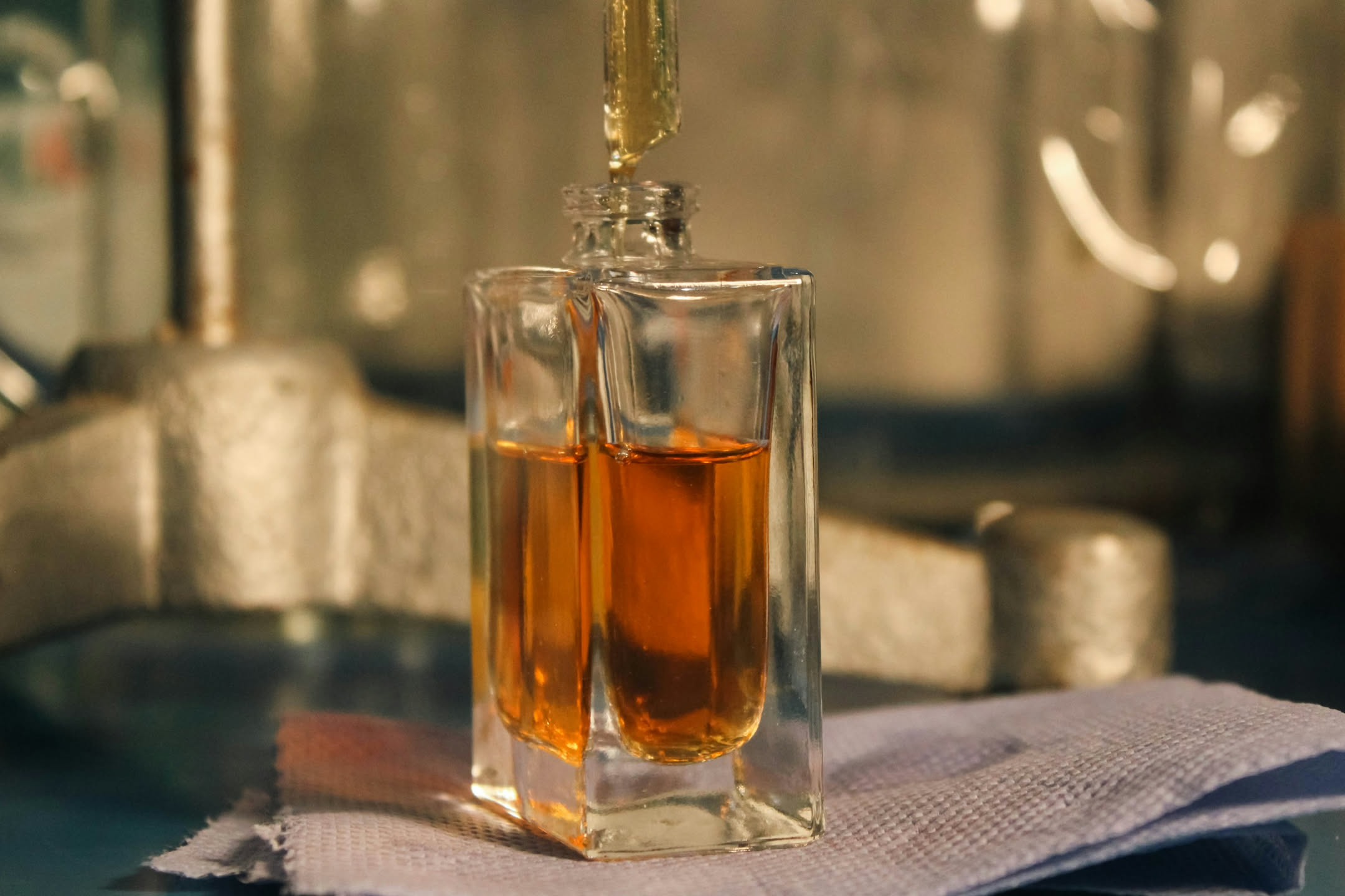 Baccelli di vaniglia accanto a un flacone di profumo ambrato su fondo scuro