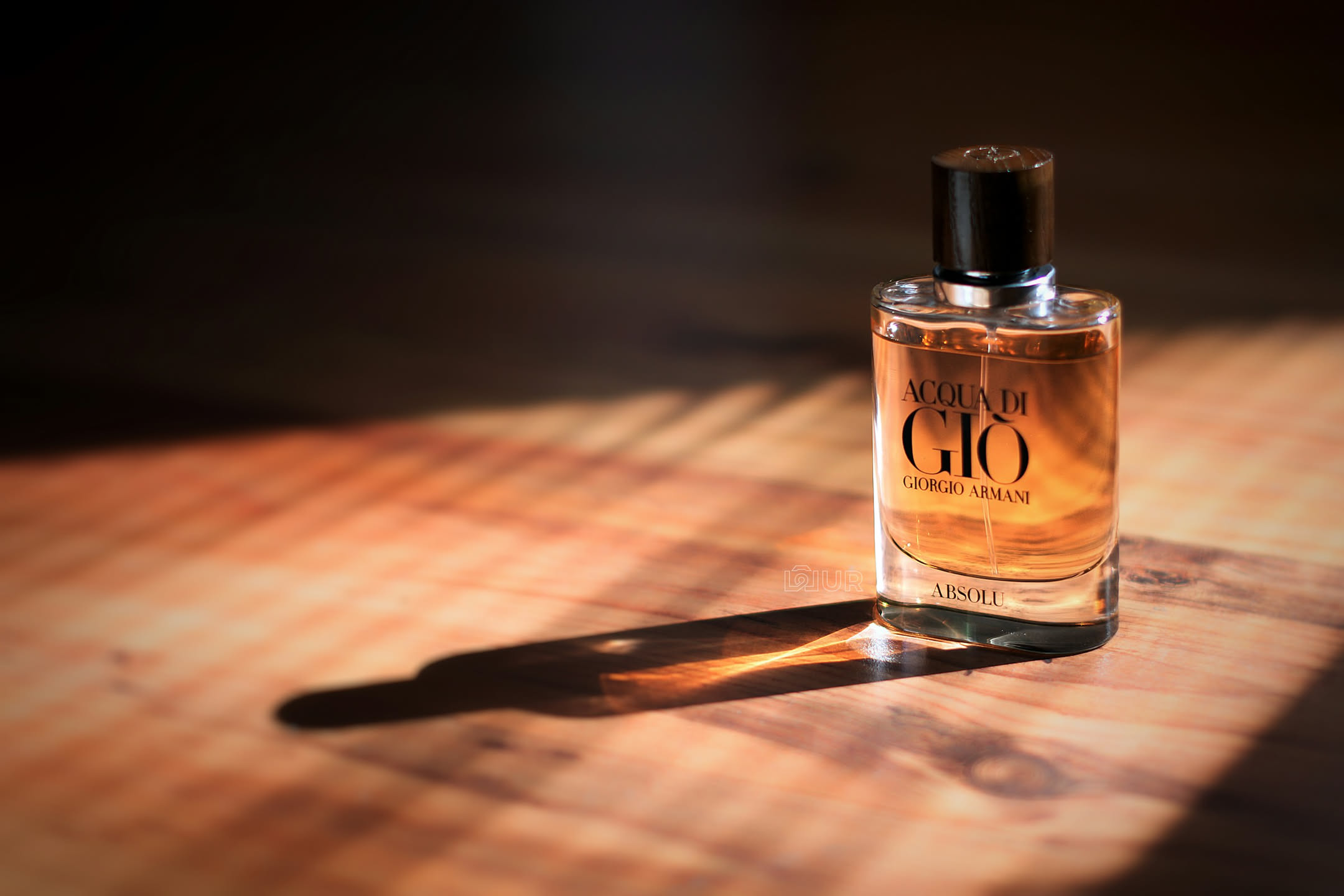 Flacone di profumo maschile accanto a legni, spezie e agarwood su fondo sobrio